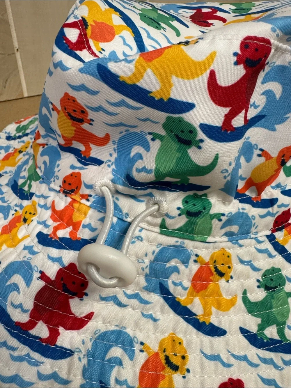 Amazon Kids' White Bucket Hat with Multicolor Surfing Dinosaurs